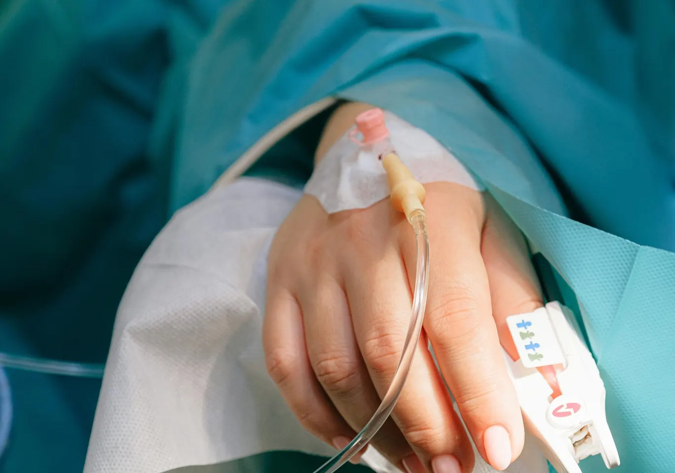 Odtrucie alkoholowe Krosno: dłoń z wenflonem i pulsoksymetrem pod nadzorem